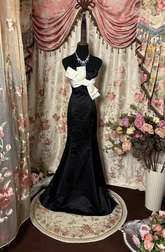 Chic black satin mermaid prom dress with strapless neckline and white bow.
