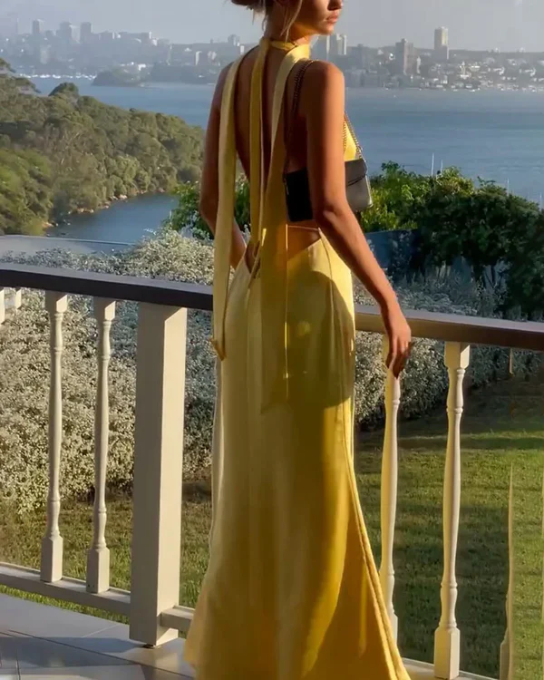 Close-up of the deep-plunge halter neckline and open-back tie detail on a yellow satin prom dress.
