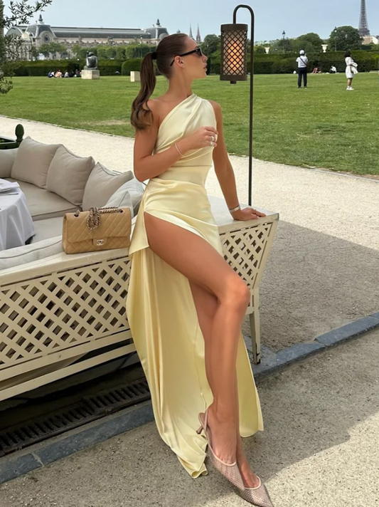 Woman in elegant satin mermaid one-shoulder prom dress with open back and high slit, front view.