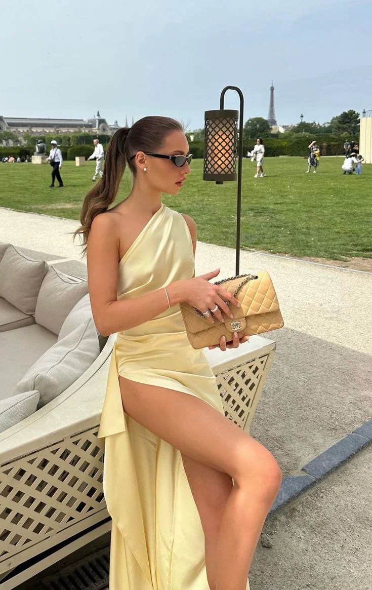 Woman in elegant satin mermaid one-shoulder prom dress, back view highlighting open back.