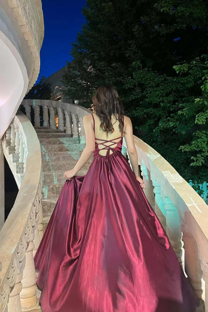 Model wearing a lustrous satin A-line evening dress, showing the lace-up back and high slit.