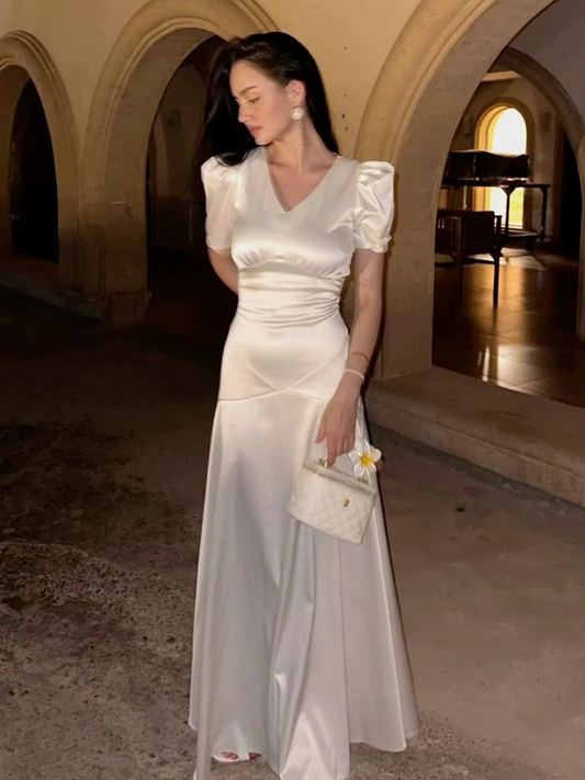 Model wearing a lustrous white satin A-line prom dress with V-neck, puffed sleeves, and ruched waist.